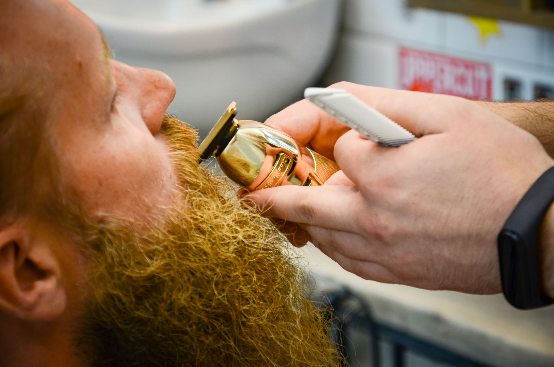 Barber expertly trims a man's beard using a razor in a close-up indoor setting.